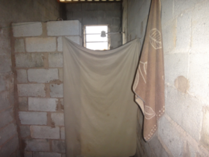 Banheiro improvisado de uma das casas, com divisória de lençol (Foto: SRTE-SP)