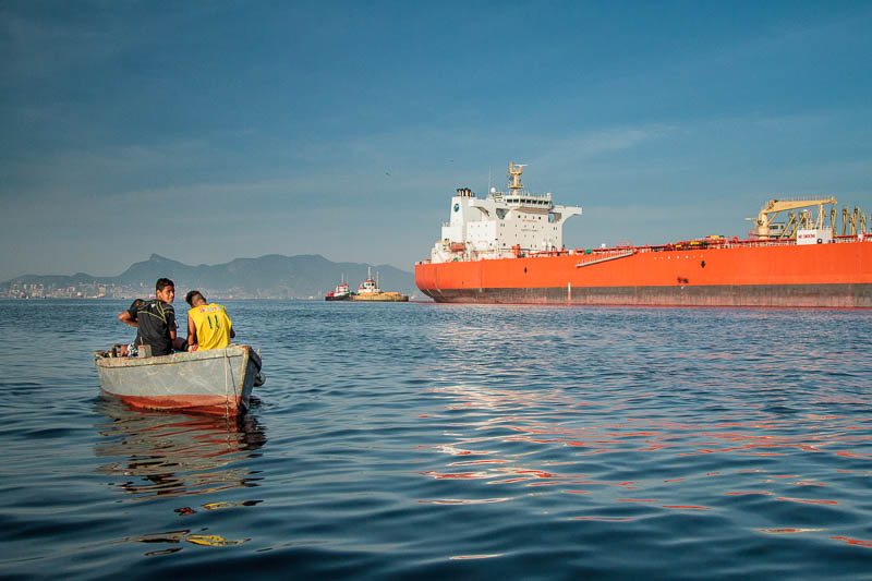 Barco de moradores locais em frente a navio petroleiro. Foto: Marcio Isensee e Sá