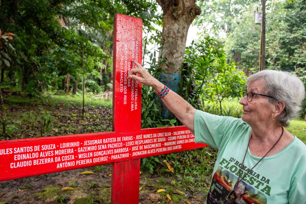 A irmã Jane Dwyer, que dá continuidade ao trabalho de Dorothy, mostra cruz ao lado do túmulo da freira, onde são colocados os nomes das vítimas da violência no campo em Anapu (PA): três delas assassinadas em 2019 (Foto: Cícero Pedrosa Neto/Amazônia Real)
