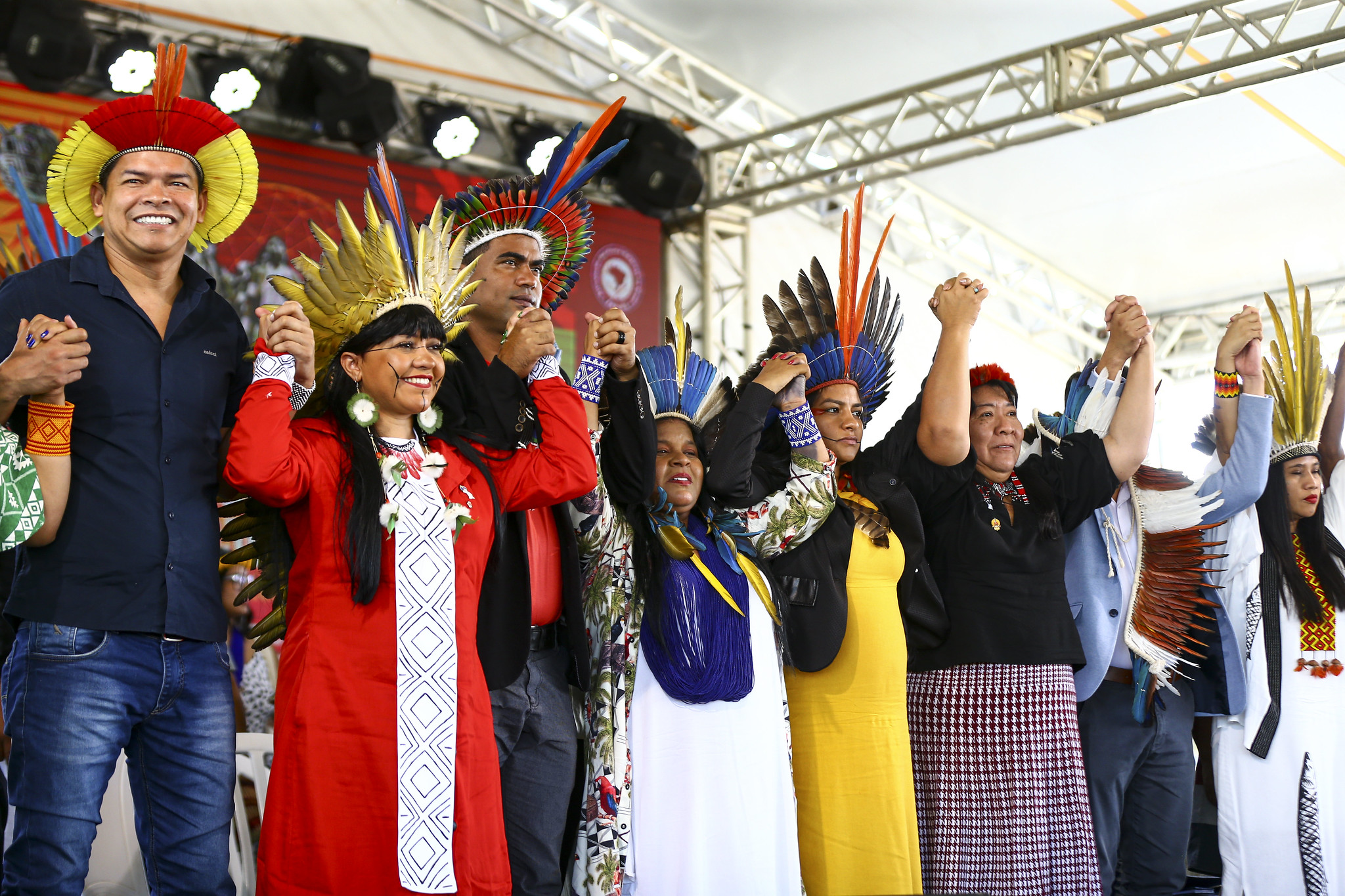 Ministra Sonia Guajajara sorrindo e de mãos dadas com indígenas em evento