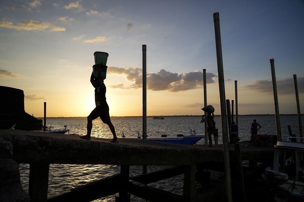 Homens descarregando no fim de tarde paneiros cheios de açaí fresco, na feira do açaí no Ver-o-Peso (Foto: Fernando Martinho/Repórter Brasil)