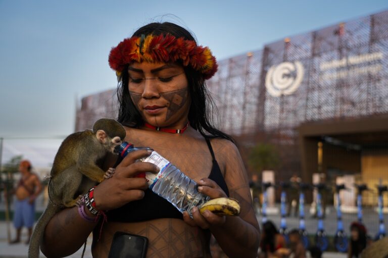 Retrato da jovem Angélica Karo dando água para macaco durante protesto dos Munduruku na entrada da Blue Zone, na COP30 (Foto: Fernando Martinho/Repórter Brasil)