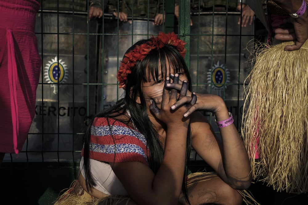 Jovem Munduruku durante protesto, agachada junto ao bloqueio do Exército, na entrada da Blue Zone (Foto: Fernando Martinho/Repórter Brasil)