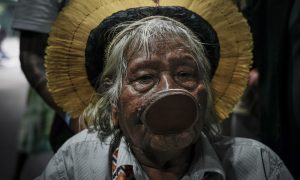 Retrato do cacique Raoni Metuktire, uma das principais lideranças indígenas do Brasil, chegando de cadeira de rodas para negociar com o presidente da COP30, André Corrêa do Lago, na Blue Zone (Foto: Fernando Martinho/Repórter Brasil)