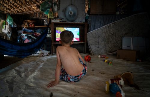 Menino assiste a desenhos animados no barraco de lona em que vive com a família no Acampamento Nova Aliança, em Itanhangá, no Mato Grosso. Desde 2014, cerca de 70 famílias sem terra vivem em um único lote a espera de uma decisão do Incra (Foto: Fernando Martinho/Repórter Brasil)